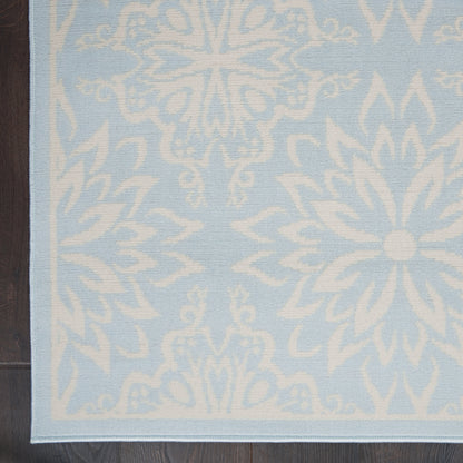 Light blue rug with white snowflake and medallion motifs and a pale border.