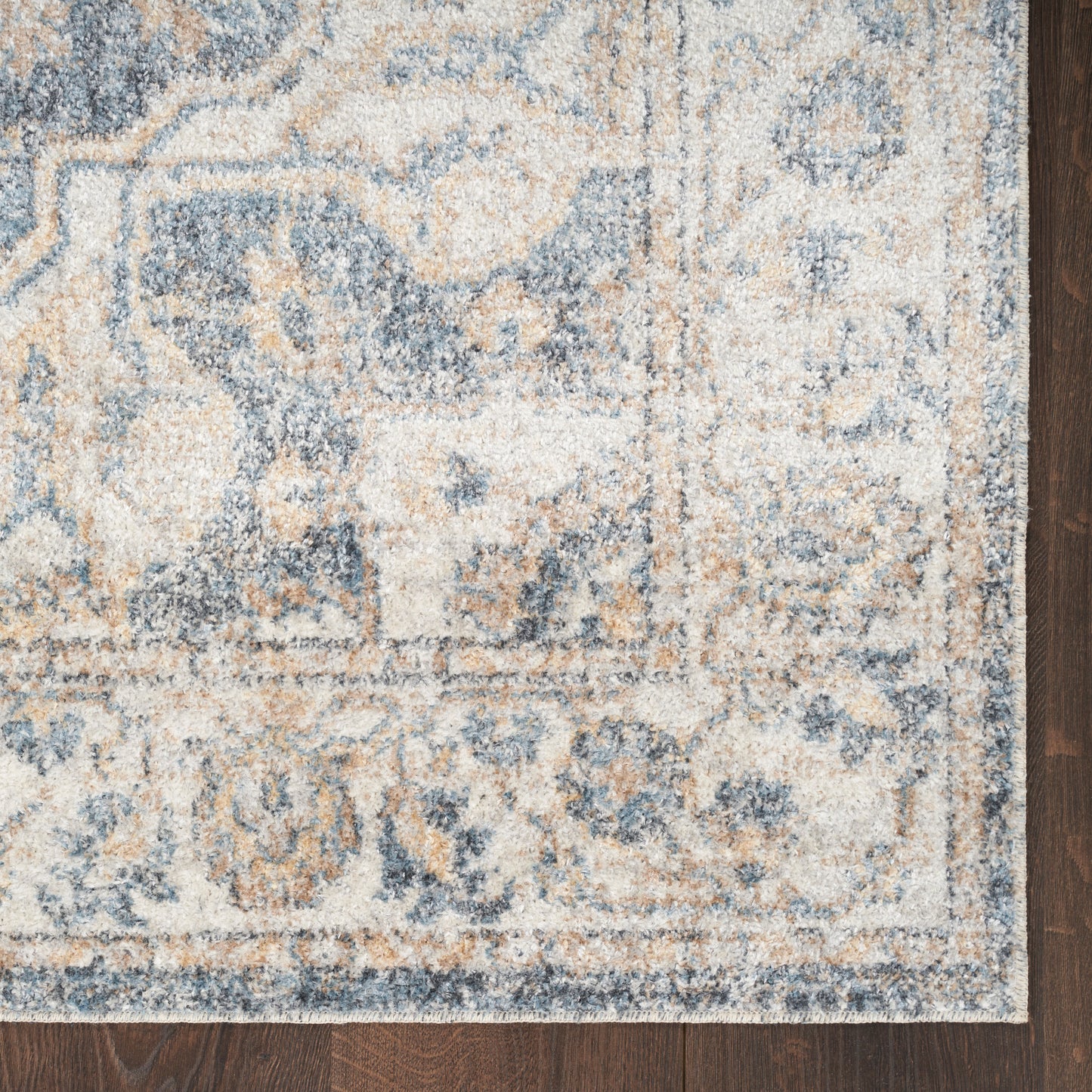 Blue & beige ornate area rug with floral motif & border on dark wood floor