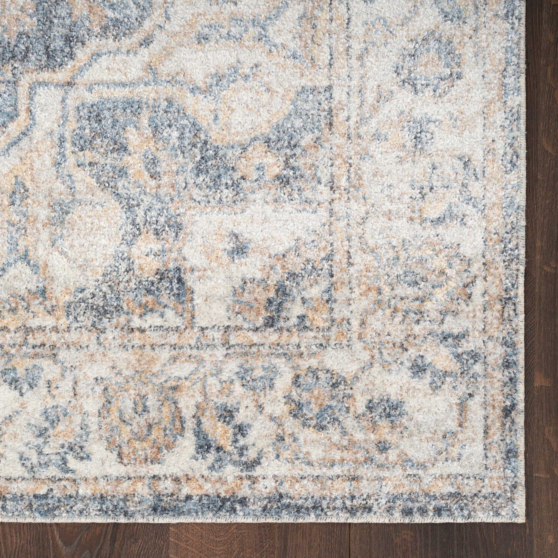 Blue & beige ornate area rug with floral motif & border on dark wood floor