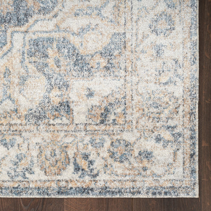 Blue & beige ornate area rug with floral motif & border on dark wood floor