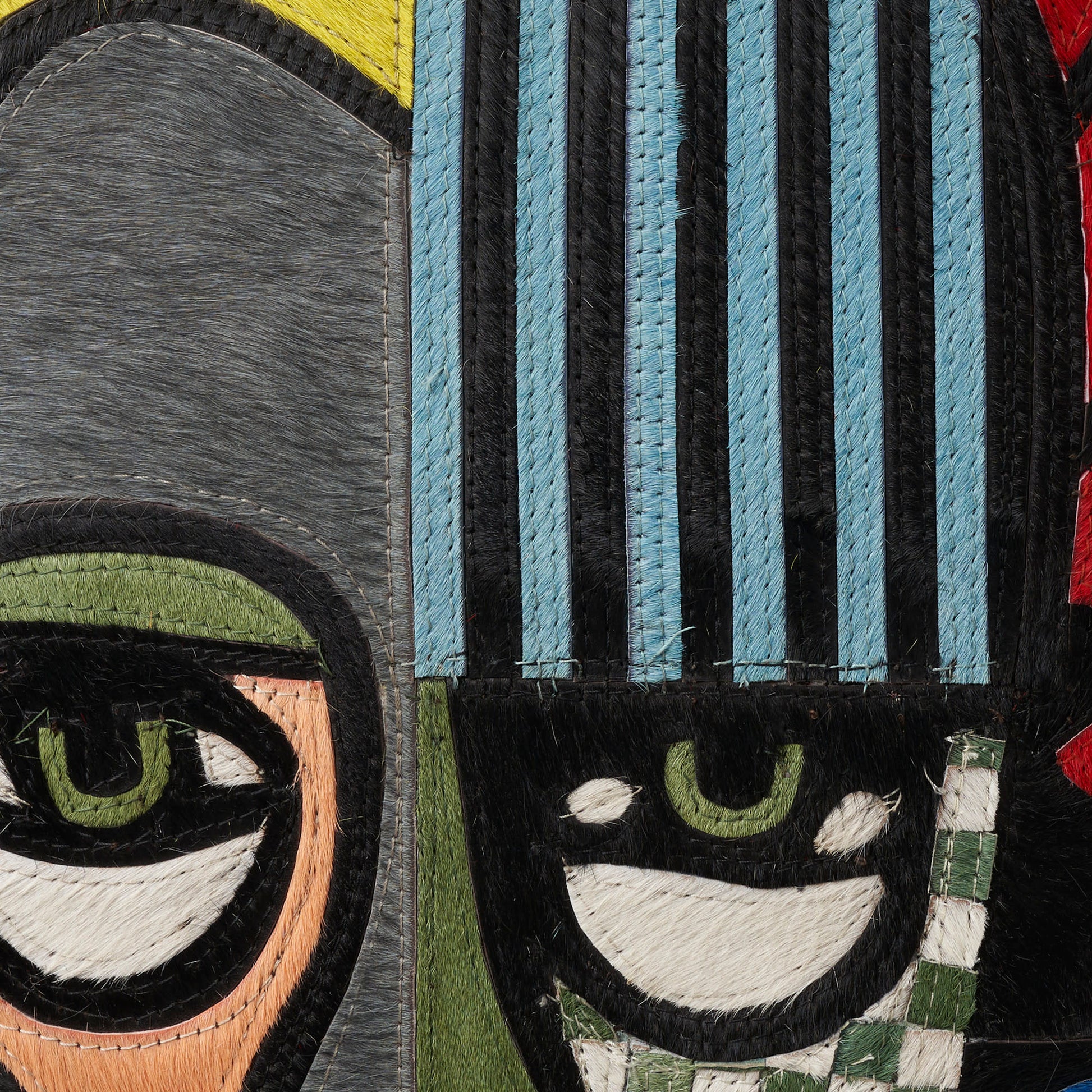 Patchwork rug with blue striped panels, gray and olive patches, and embroidered eye motifs.