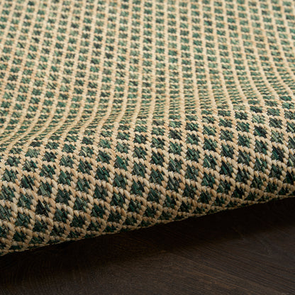 Beige and green woven rug with geometric diamond pattern, natural fiber texture, laid on dark wood floor.