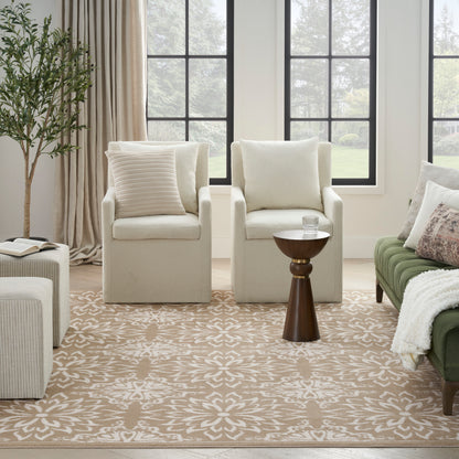 Bright living room with cream armchairs, beige floral rug, a small dark wood side table, and a green sofa by windows.