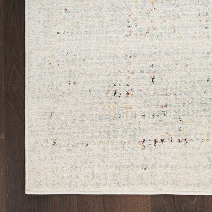 Beige speckled area rug with tiny multicolor flecks on dark wood floor; modern minimalist style.