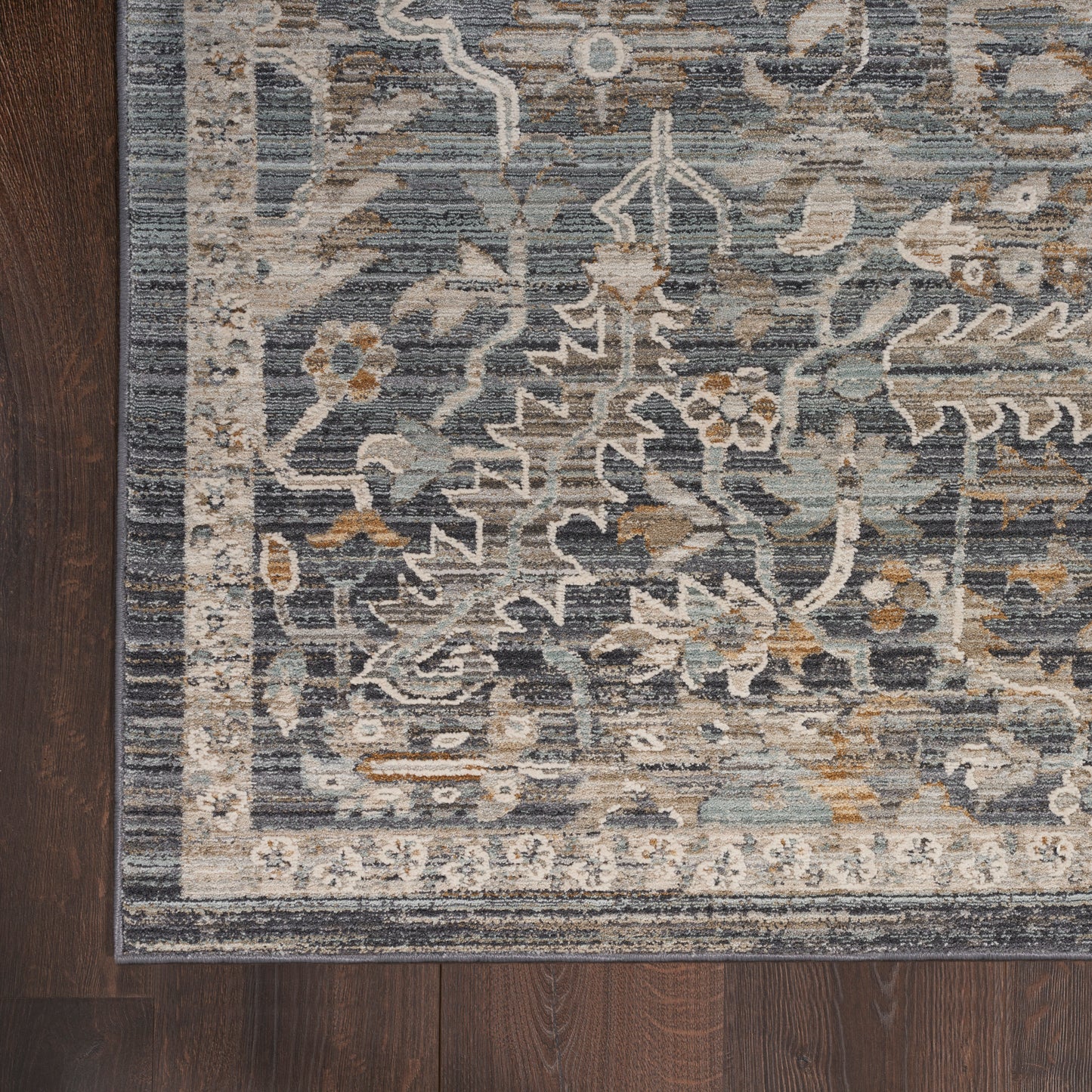 Blue and ivory oriental rug with floral motifs and beige border on dark wood floor.