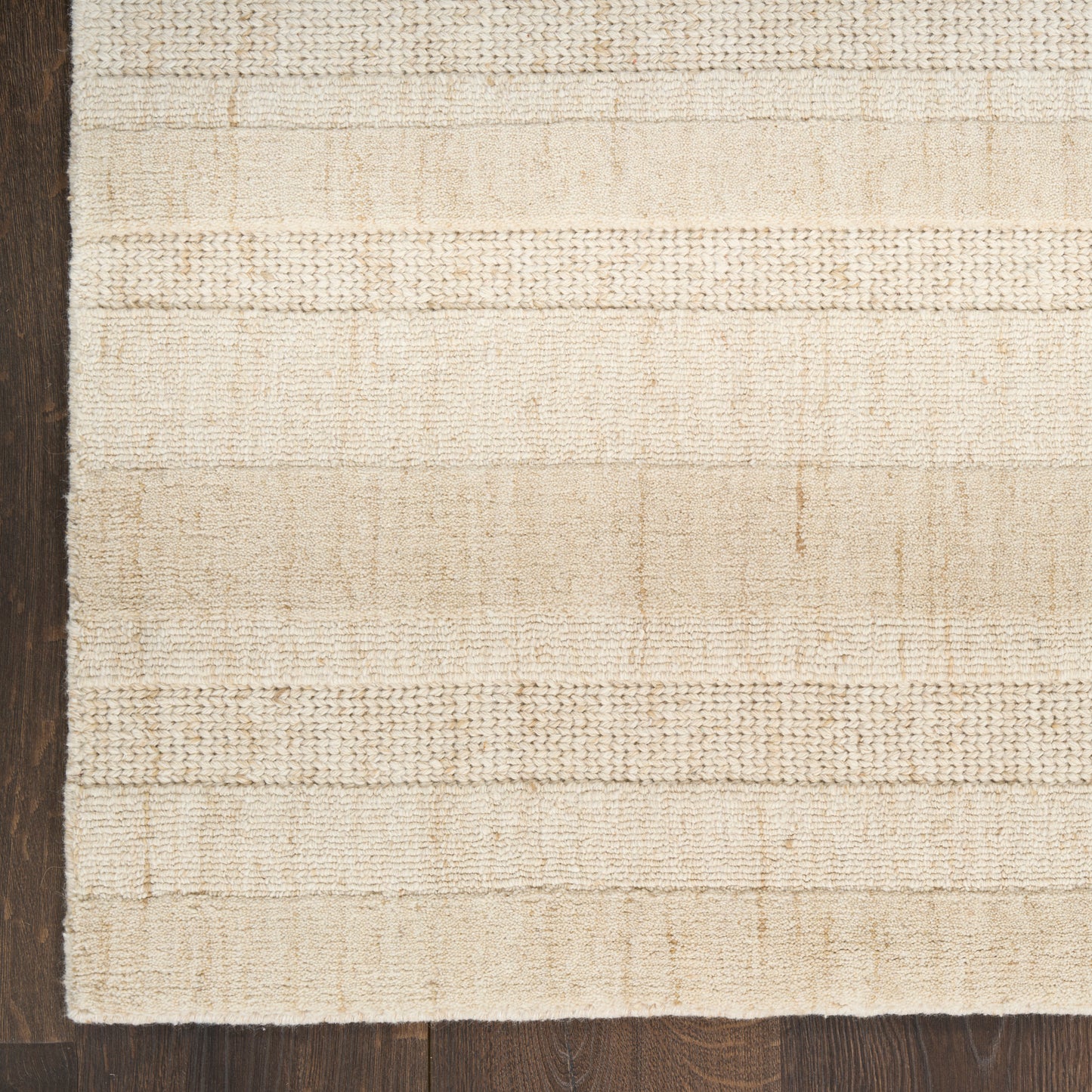 Cream and beige woven rug with subtle horizontal stripes on dark wood floor; textured flatweave.