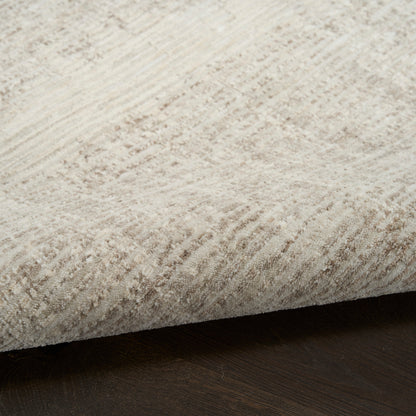 Beige textured area rug with soft pile and visible edge on dark hardwood floor.