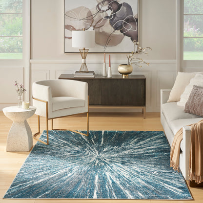 Blue starburst rug on wood floor in a modern neutral living room with cream chair, beige sofa & abstract art.