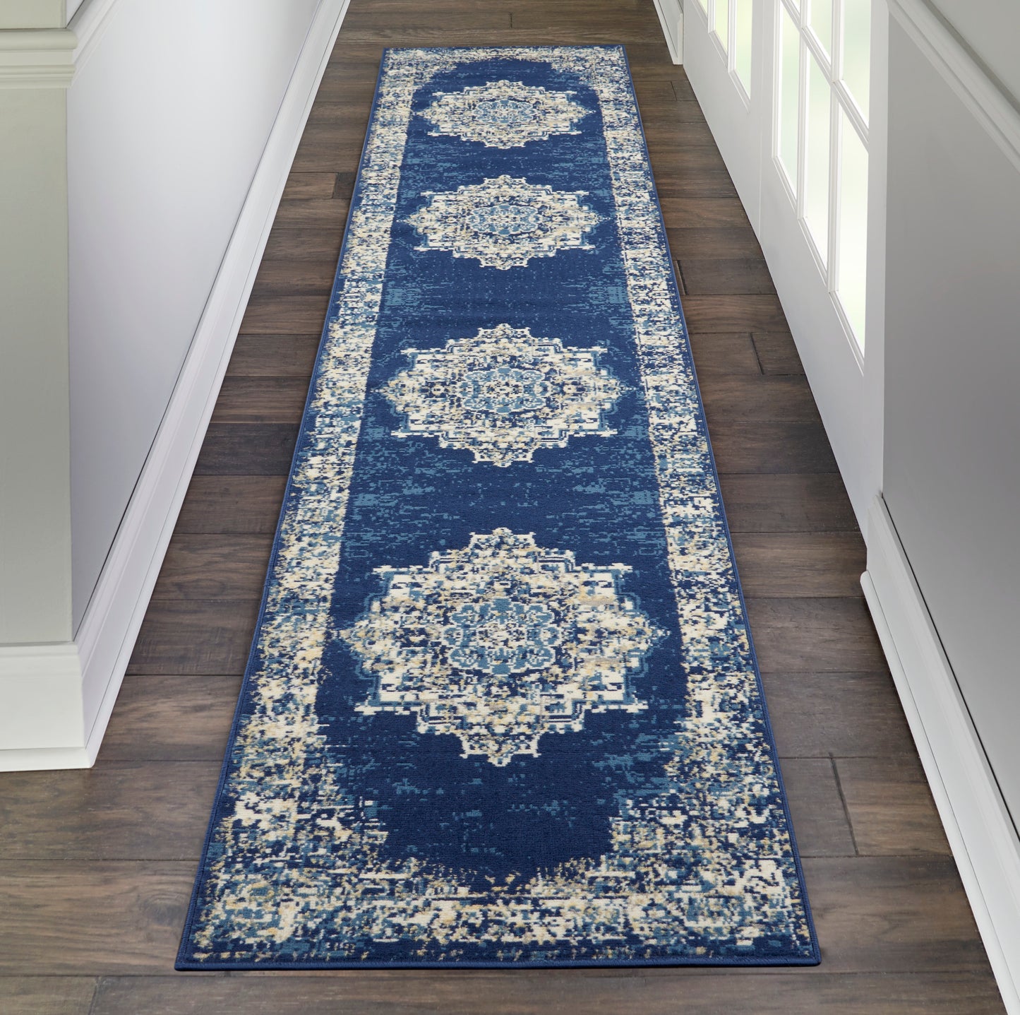 Navy blue hallway runner rug featuring large ivory medallion motifs and a light distressed border.