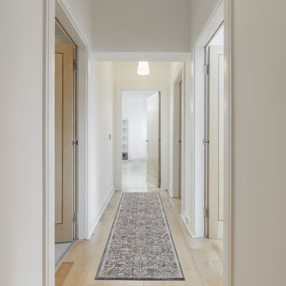 Bright hallway with white walls, light wood doors, pale wood floor, blue-gray patterned runner rug.