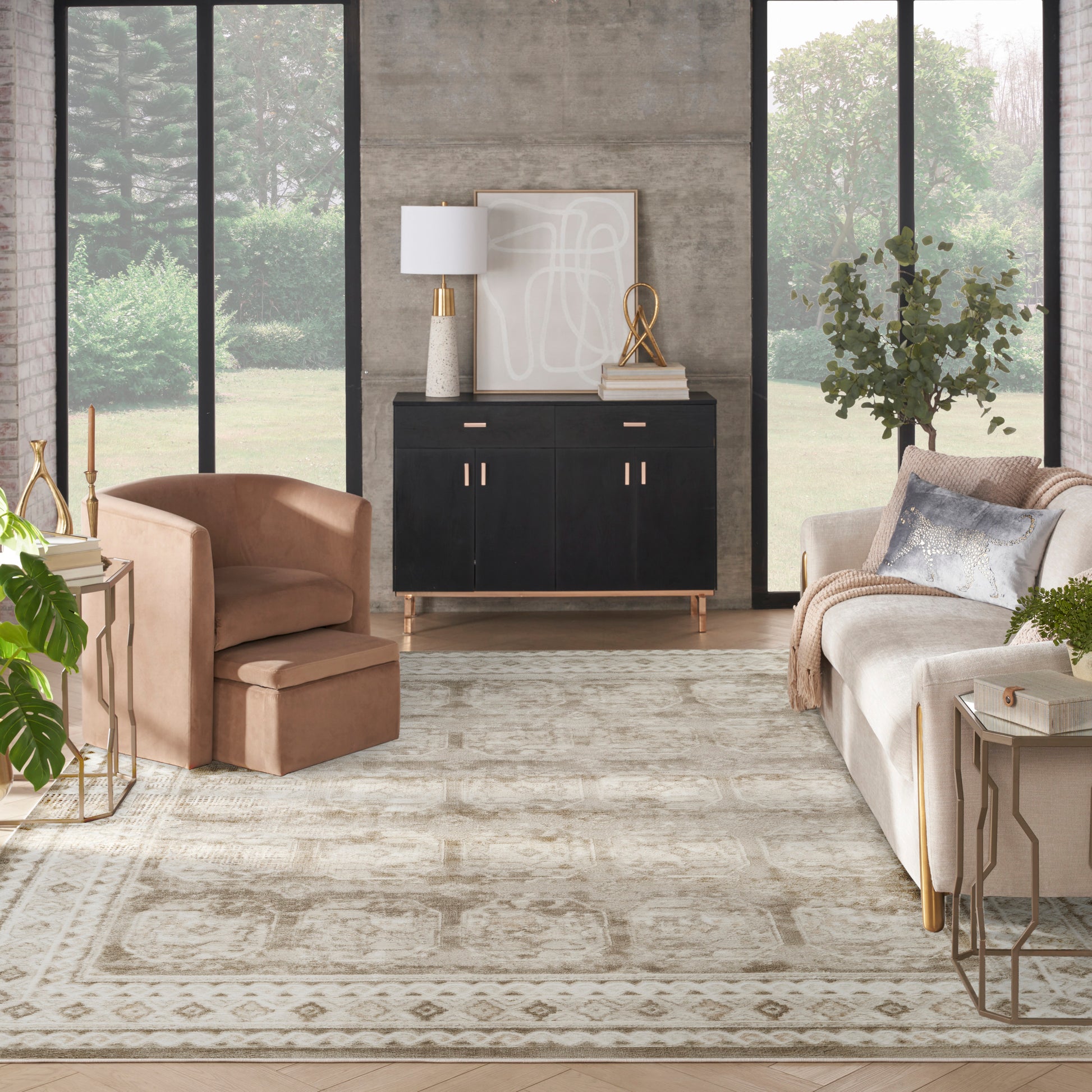 Modern living room with beige seating, black sideboard with gold handles, abstract art, lamp, plants, and a patterned rug.