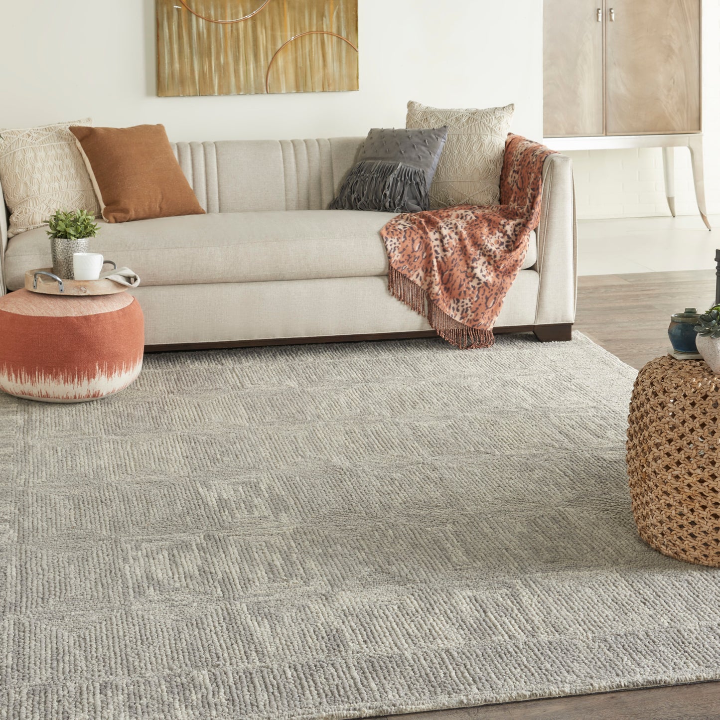 Cozy living room with beige sofa, textured gray rug, leopard print throw, rust pillows, orange round ottoman and woven basket