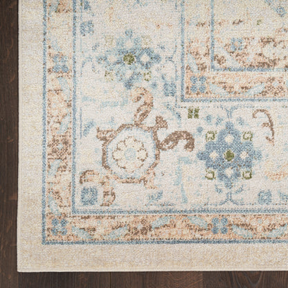 Corner view of a pale beige rug with blue floral border and medallion on dark wood floor.