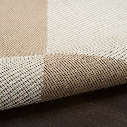 Beige and ivory checkered woven textile with thin dark stripes, folded on a dark wood surface.