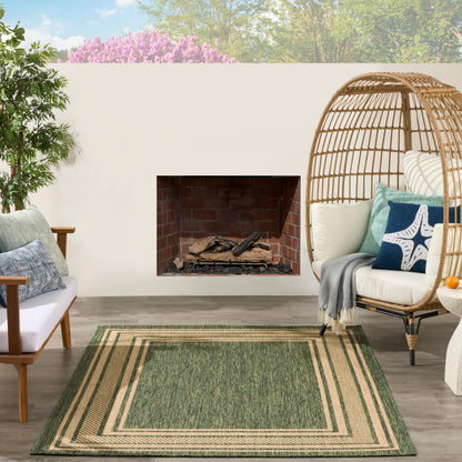 Outdoor patio featuring a green beige striped rug with woven rattan egg chair, cream cushions, wood seating, and a brick fireplace.