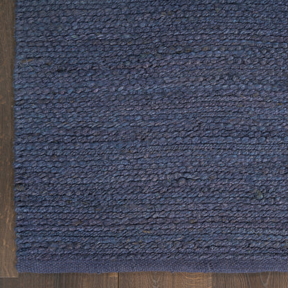 Blue loop-pile rug with a darker navy border on wood floor; dense textured weave for living areas.