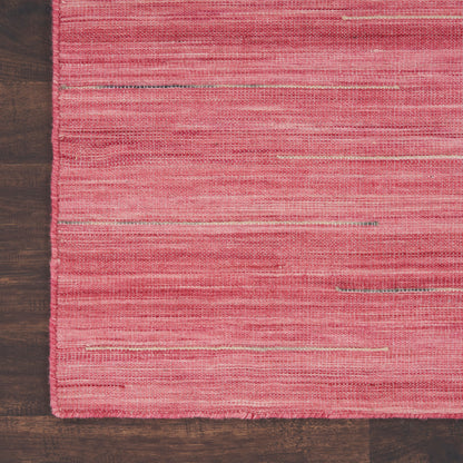 Pink woven area rug with subtle horizontal stripes on dark wood floor.