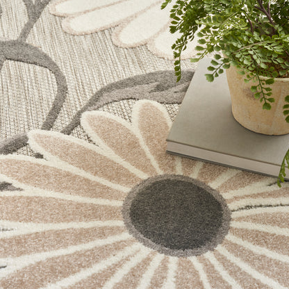 Beige and cream sunburst floral rug with a dark gray center; plant and books rest on top.