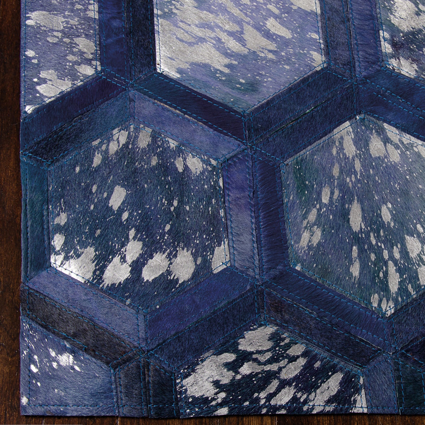 Denim blue hexagon rug with patchwork panels & ivory speckle pattern, dark blue seams, rustic hex tile design.