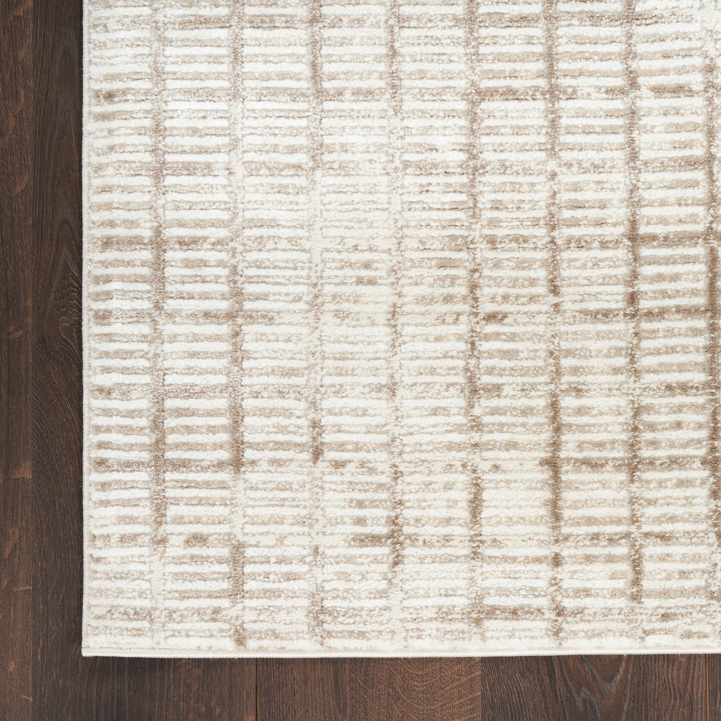 Beige textured area rug with taupe grid pattern, rectangular and soft, placed on dark wood floor