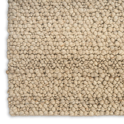 Beige loop-pile rug close-up; dense tufted texture with cream-tan fibers, soft and plush.