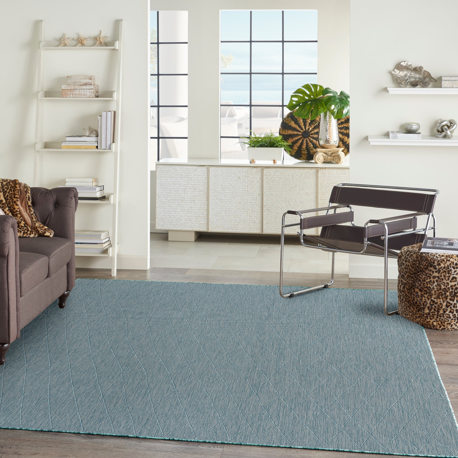 Blue textured area rug with diagonal stitching in a sunlit mid-century living room; leather lounge chair and leopard accents.