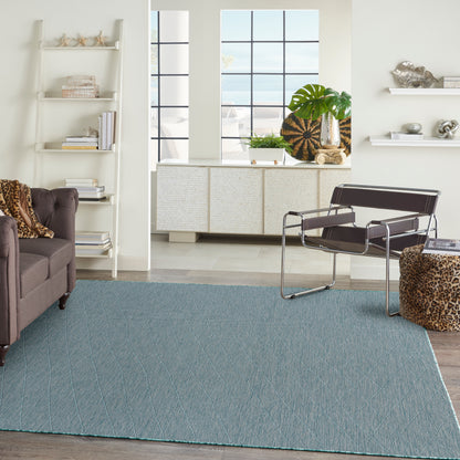 Blue textured area rug with diagonal stitching in a sunlit mid-century living room; leather lounge chair and leopard accents.