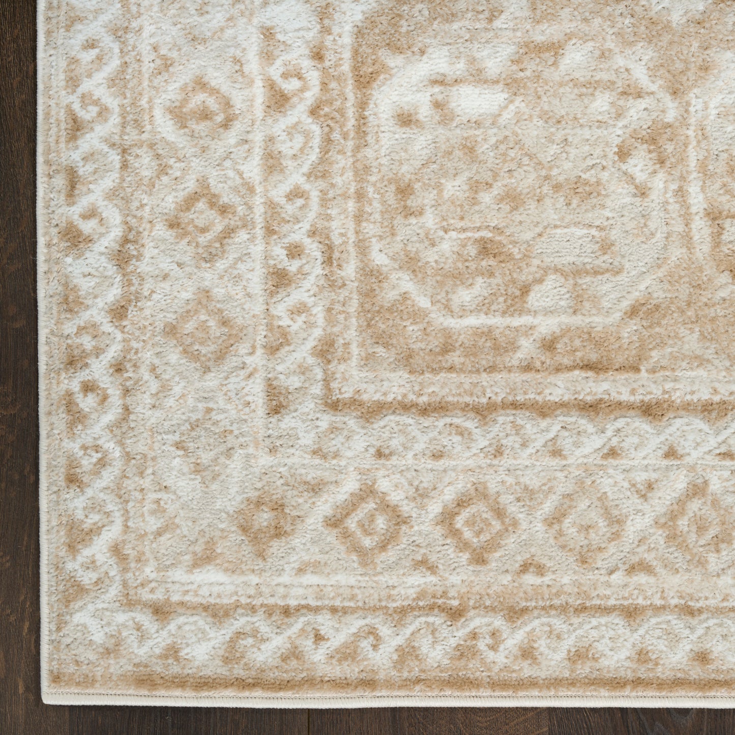 Beige and ivory geometric rug with diamond borders on dark wood floor; plush low-pile oriental-inspired design.