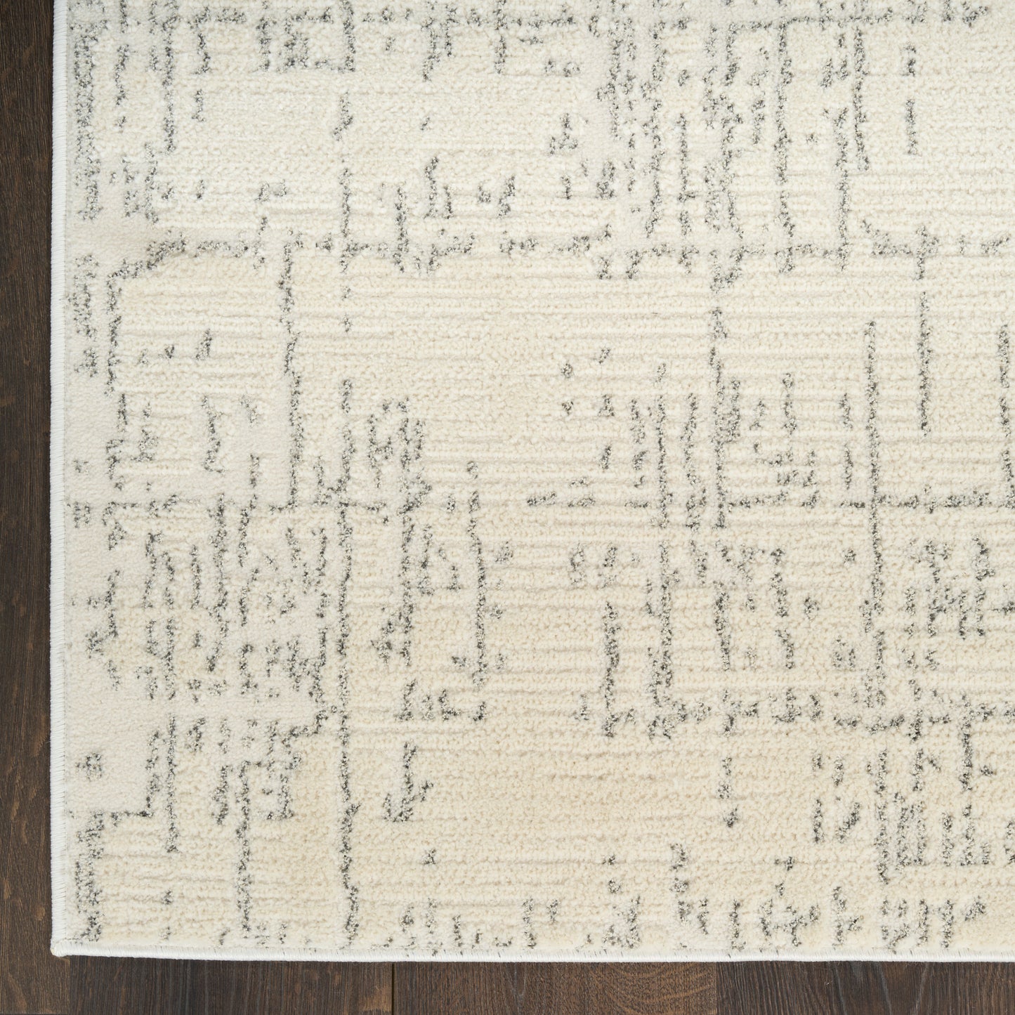 Cream area rug with a subtle gray geometric pattern on a dark wood floor; modern, soft-textured rectangle.