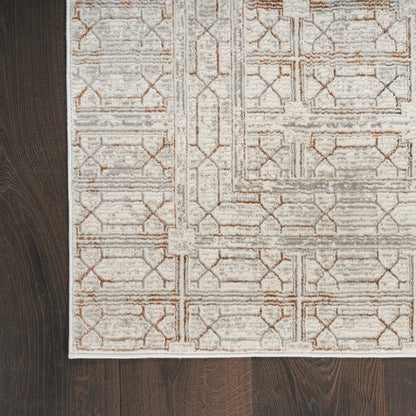 Soft ivory geometric area rug with tan lattice pattern and pale border on dark hardwood floor.