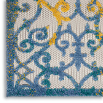 Close-up of blue and turquoise ornamental scrollwork with yellow speckles on a textured cream rug.