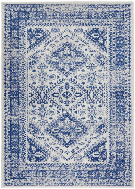 Rectangular blue-and-white distressed oriental area rug with central medallion and ornate border.