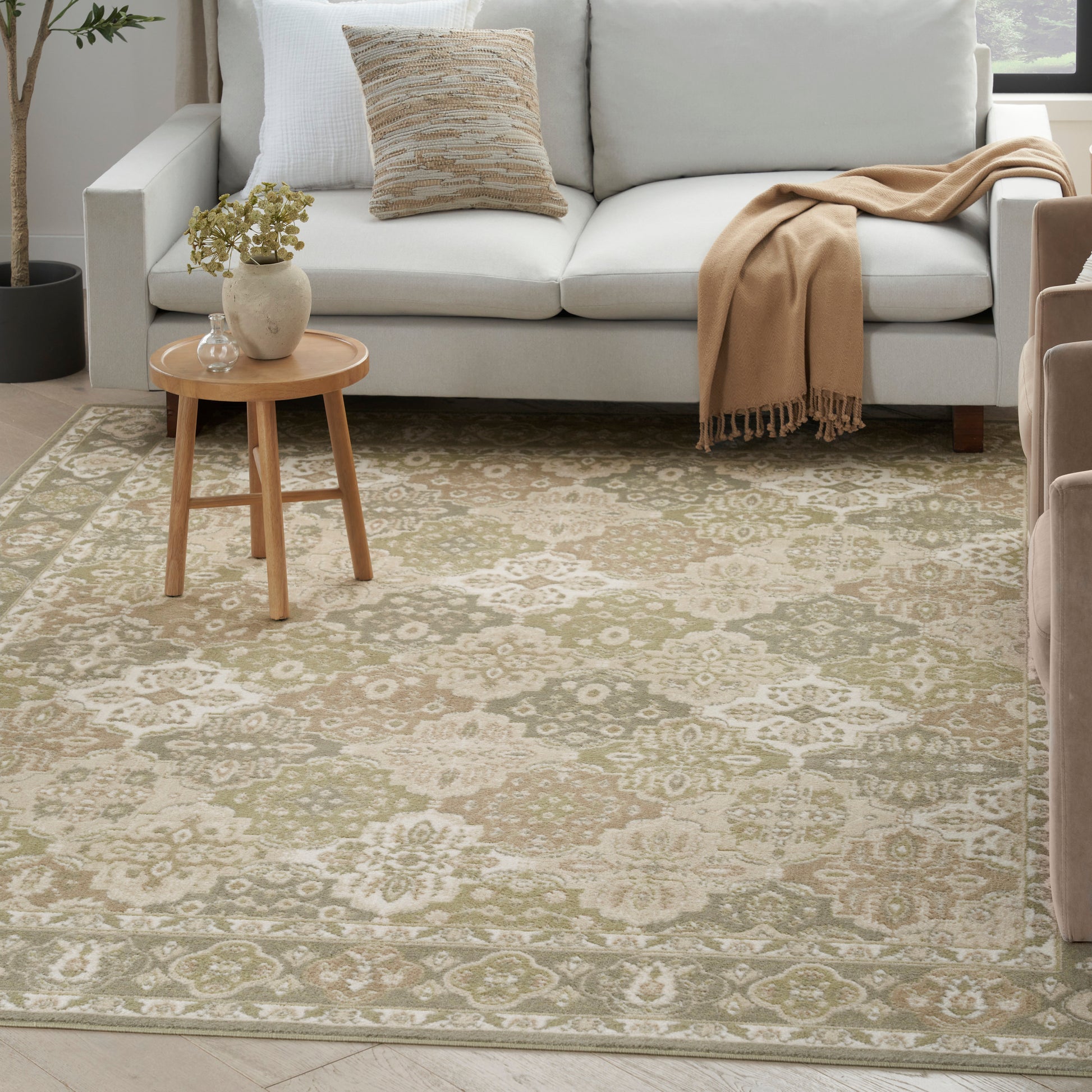 Neutral living room with beige floral-patterned rug, light gray sofa, wooden side table, and beige throw.