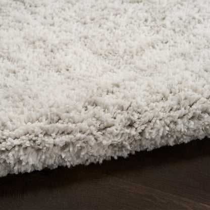 Cream shaggy rug with plush, fluffy pile on dark wood floor.