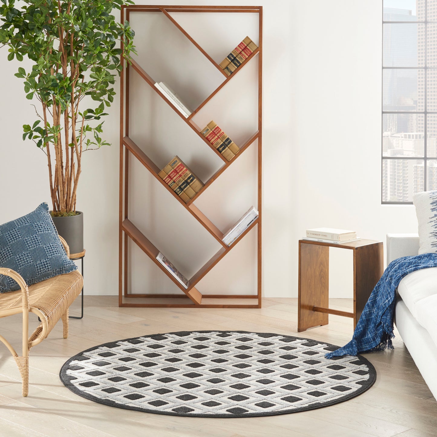 Living room with a zigzag wooden bookshelf, circular black-and-white rug, potted plant, wicker chair, and blue accents.