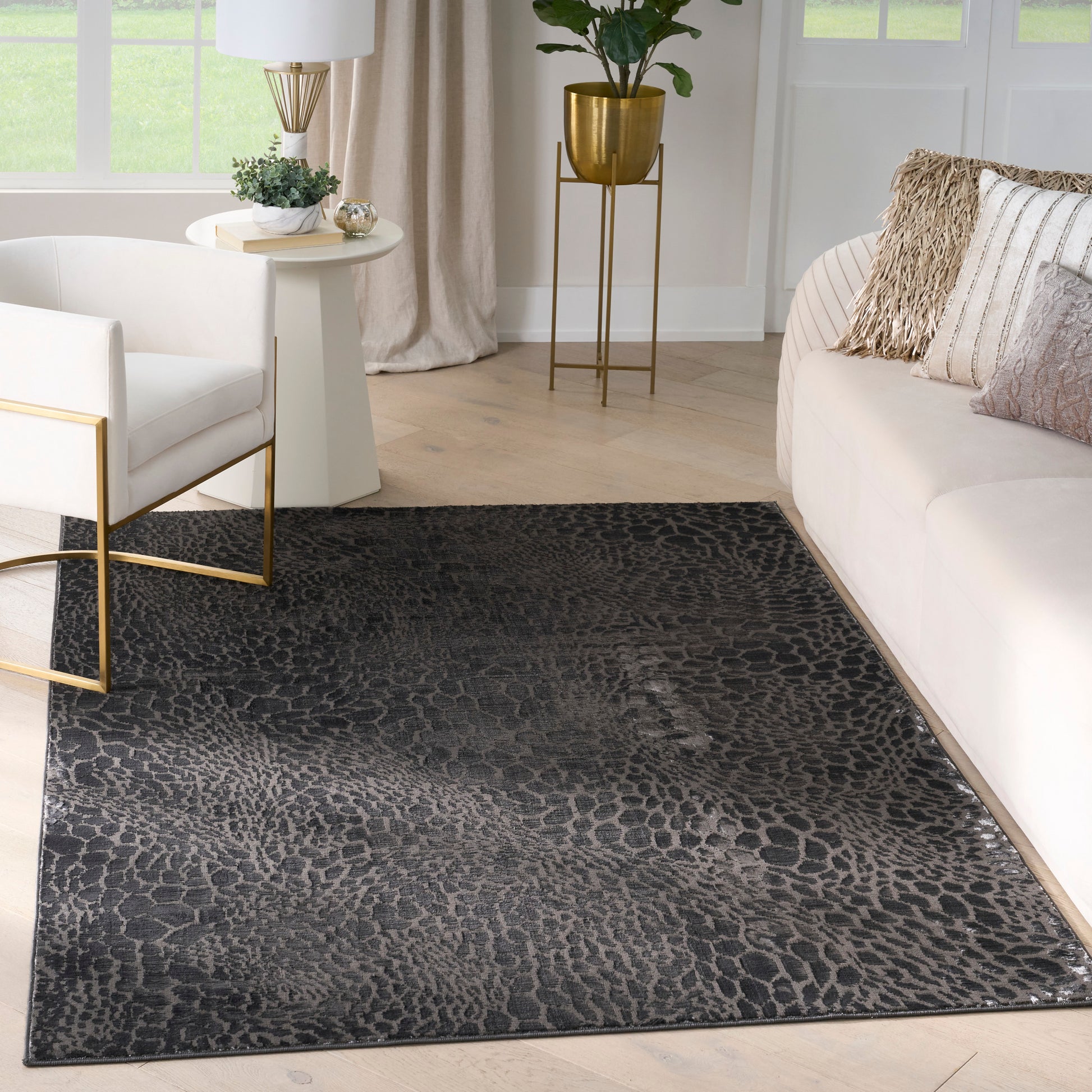 Dark leopard-print area rug in a light modern living room with cream sofa and gold metal accents.