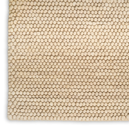 Beige loop-pile rug close-up with tiny rounded tufts and soft textured surface.