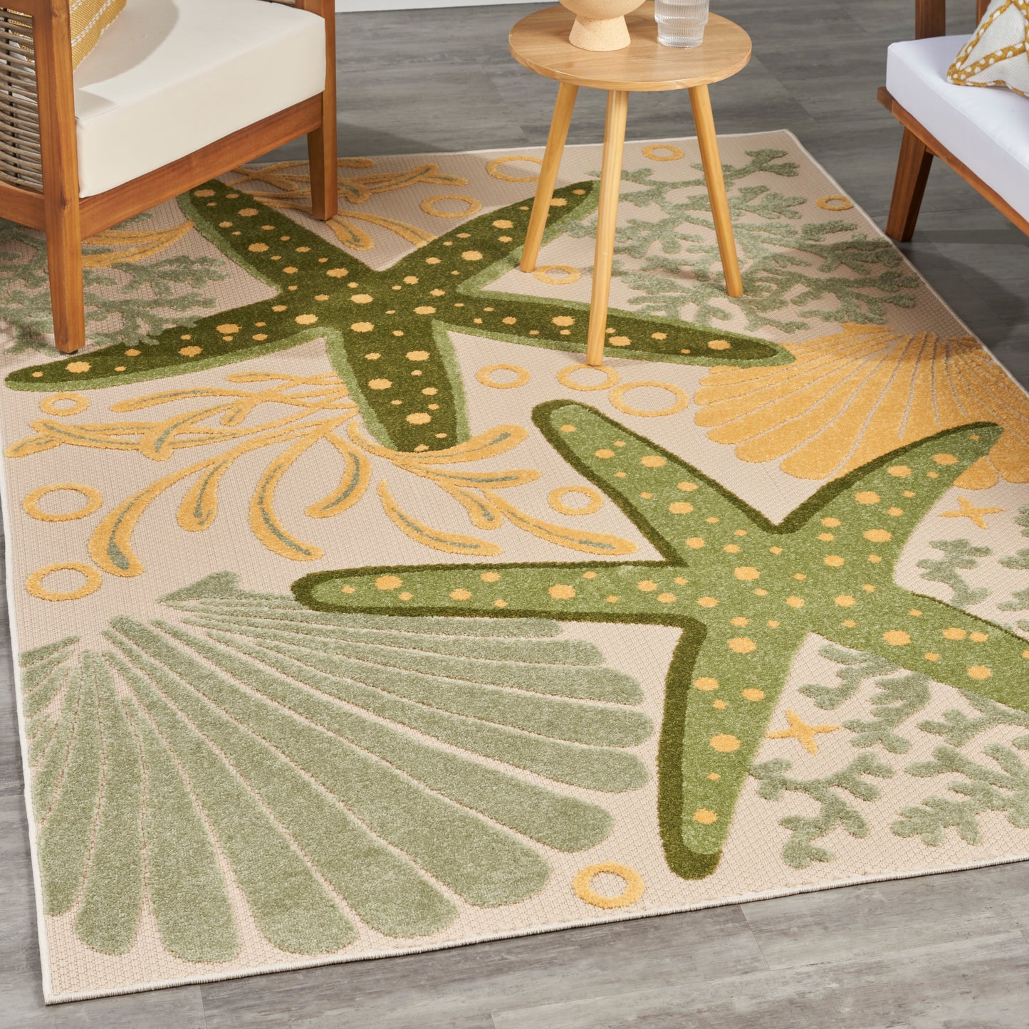 Coastal outdoor rug with beige base, large green starfish patterns and yellow shells, 4' x 6'.