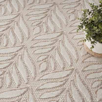 Beige leaf-patterned rug with textured pile; small potted green plant in a woven basket sits at the edge.