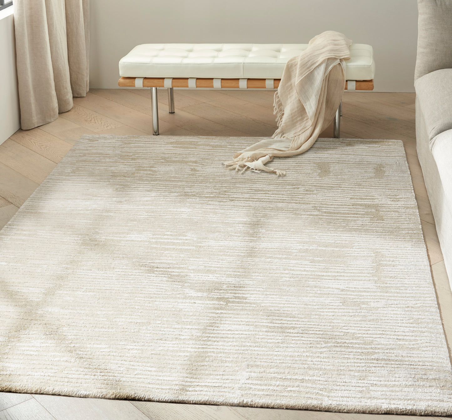 Cream textured area rug in a modern living room, paired with a white tufted bench and draped beige throw.