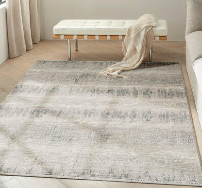 Large neutral area rug with a distressed gray-beige gradient pattern in a modern living room beside a white tufted bench.