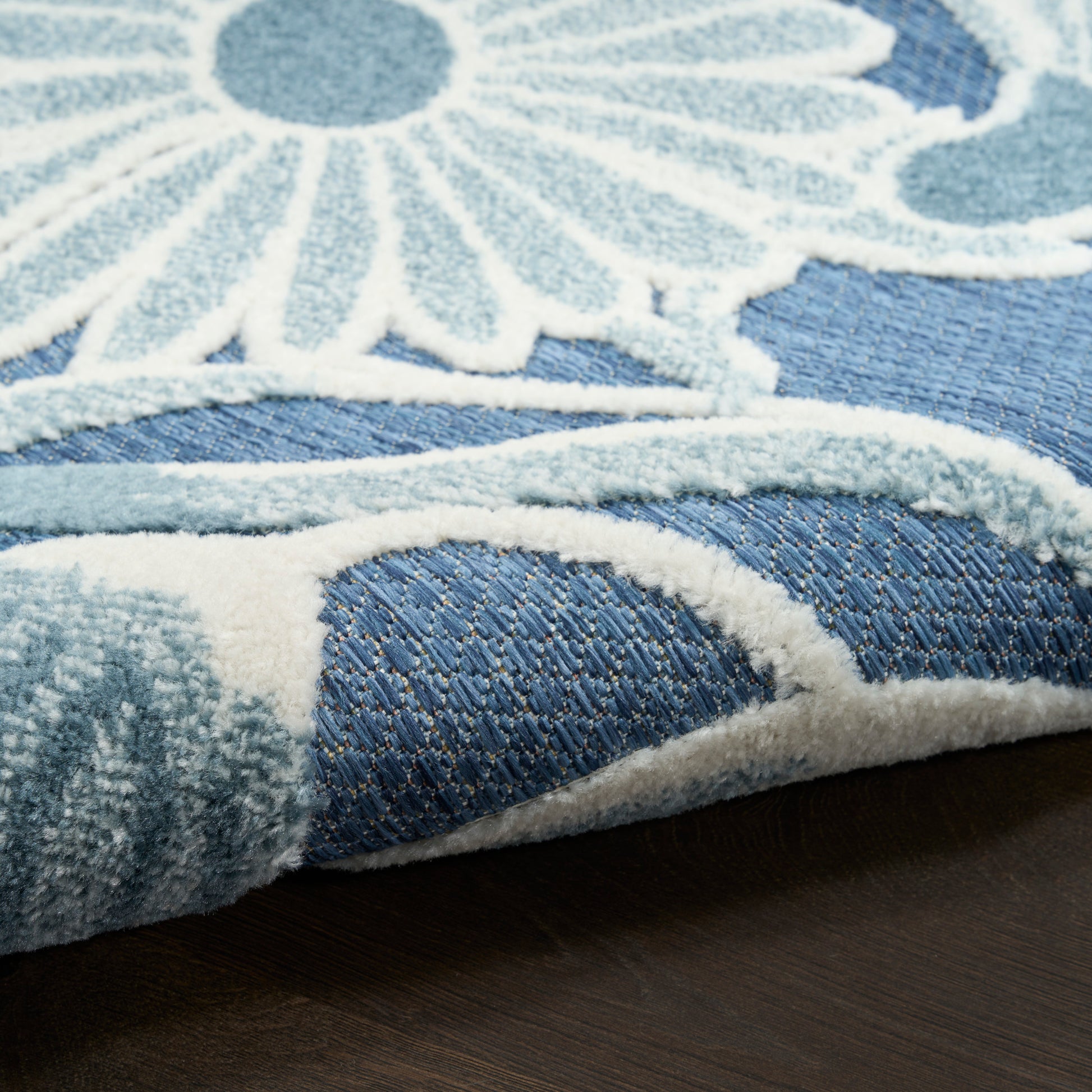 Blue outdoor rug (4' x 6') with a white raised floral pattern, plush tufted pile, rolled edge.