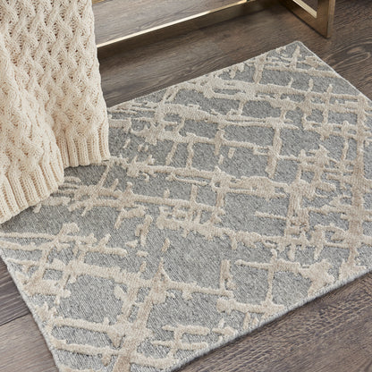 Gray rug with cream raised geometric lattice pattern; plush pile on dark wood floor beside a chunky beige knit throw
