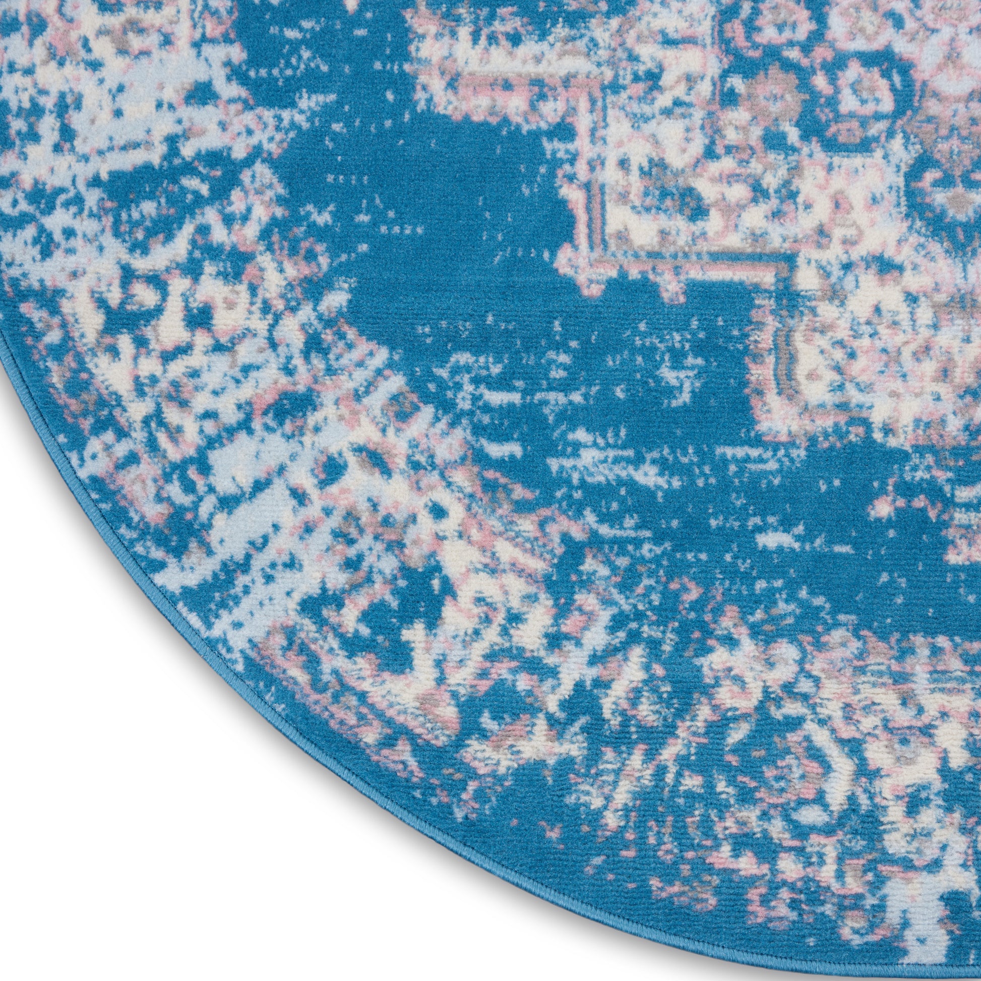 Round blue area rug with pink & white distressed motif & blue edge binding.