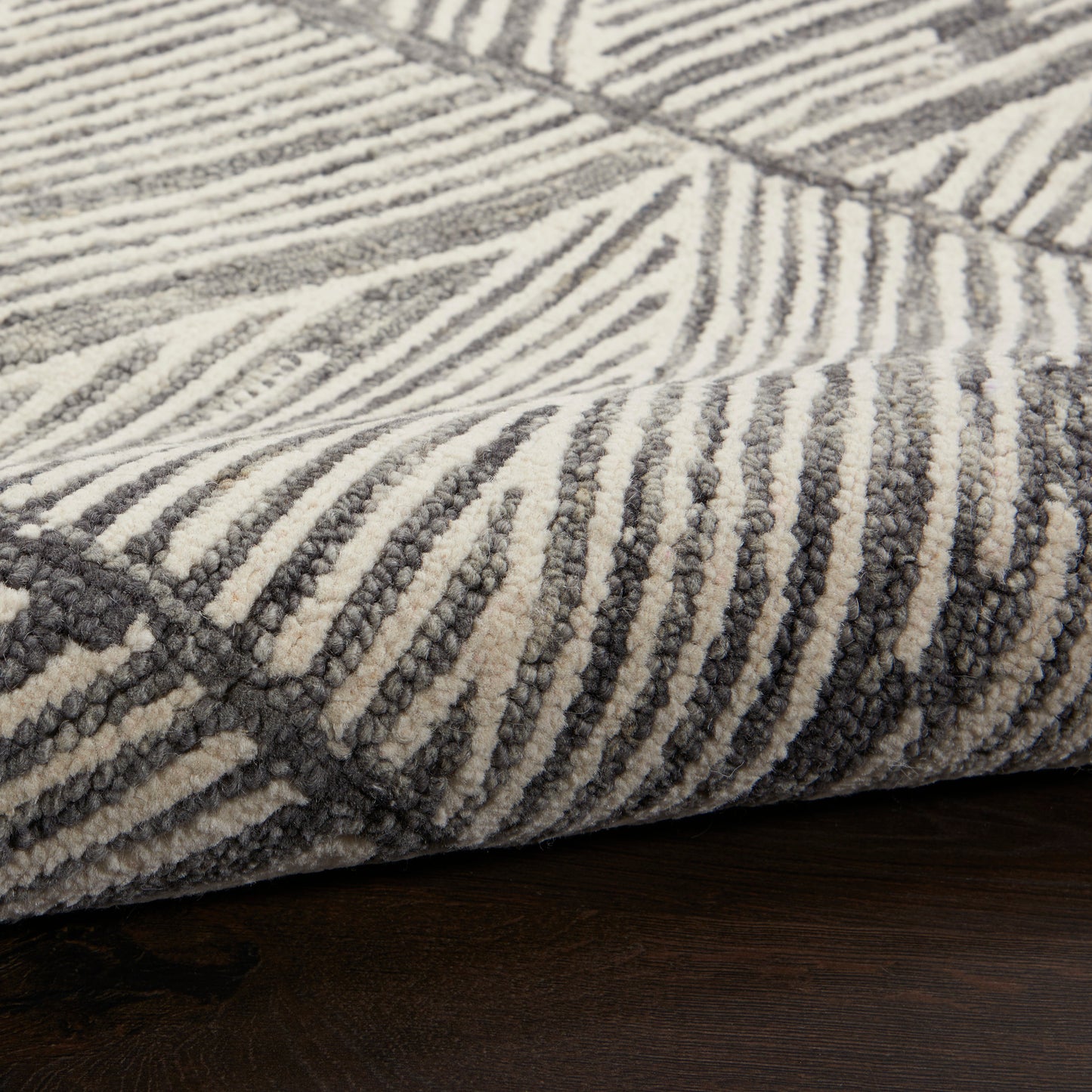 Close-up of a gray and white striped plush rug with thick pile on dark wood floor.