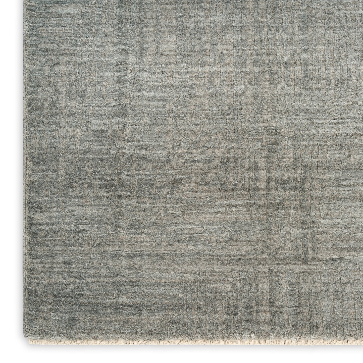 Gray-toned woven area rug with a subtle patchwork/grid pattern & cream fringe along the bottom edge.