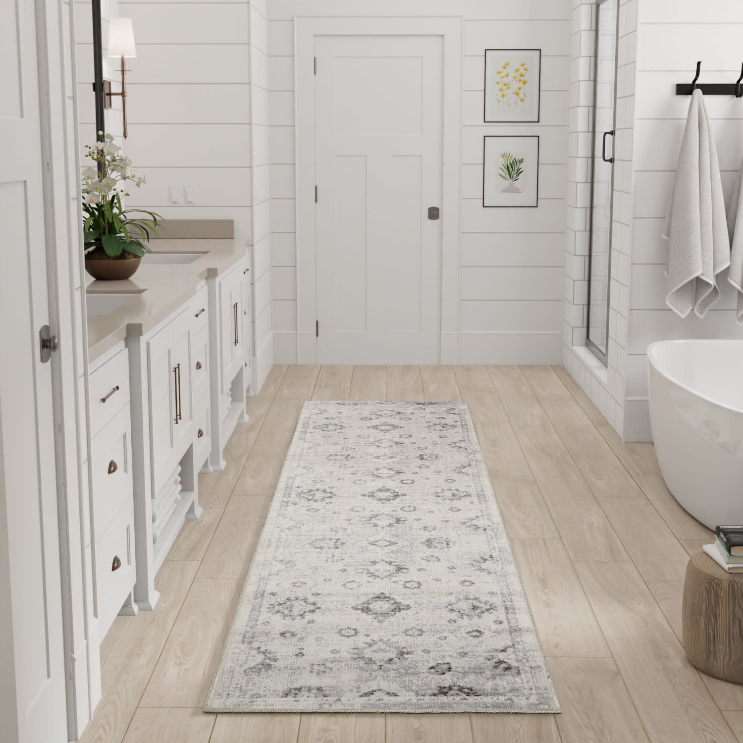 Long light gray patterned runner rug in a bright white farmhouse-style bathroom with a freestanding tub and white cabinetry.
