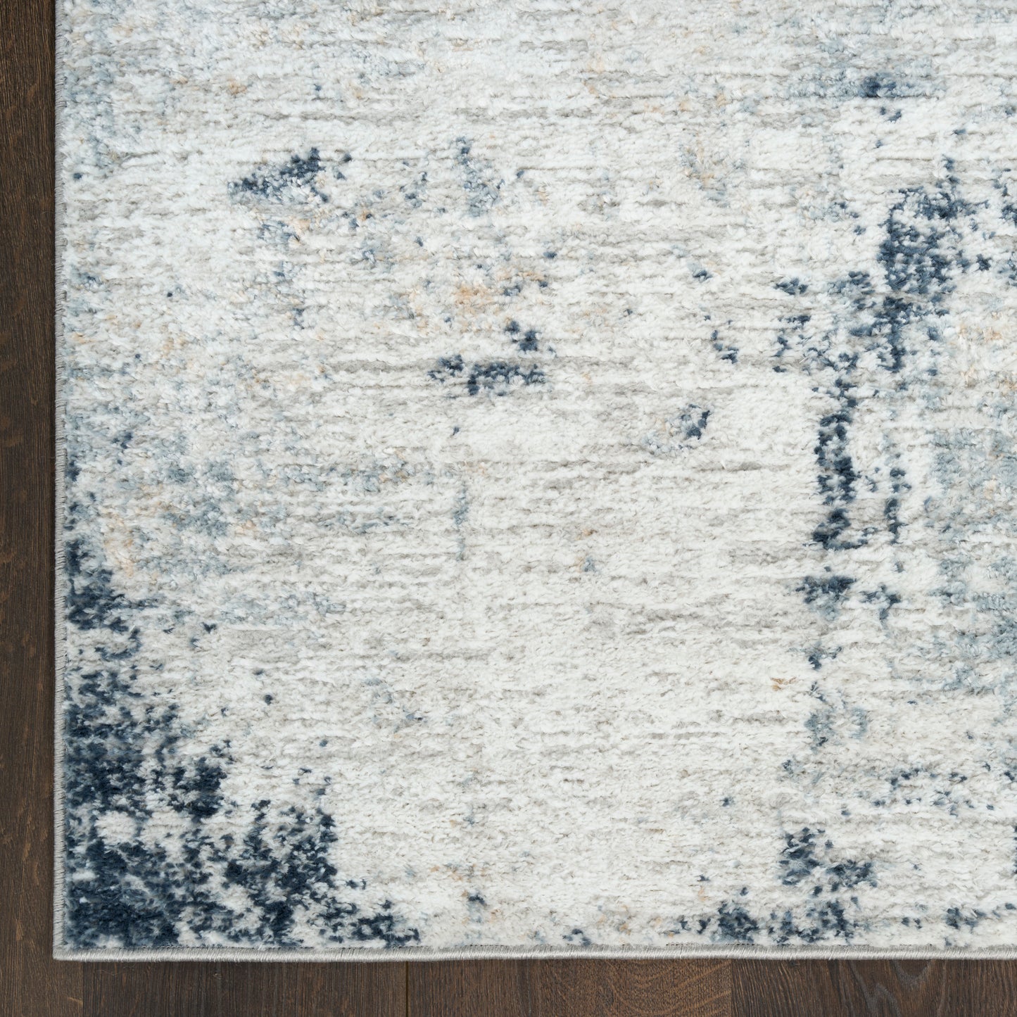 Cream and navy distressed abstract area rug on dark wood floor.
