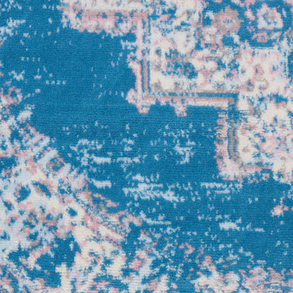 Close-up of a blue round rug with a pink and white distressed abstract pattern.