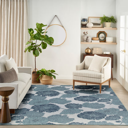 Neutral living room with blue floral rug, cream sofa, striped armchair, wicker baskets, and round wall mirror